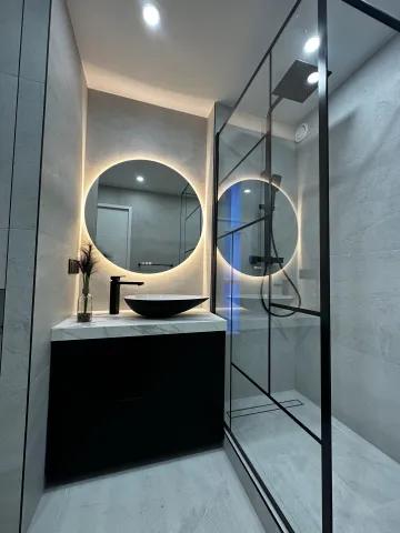Salle de bain moderne avec douche à l'italienne, paroi vitrée et miroir rond rétroéclairé